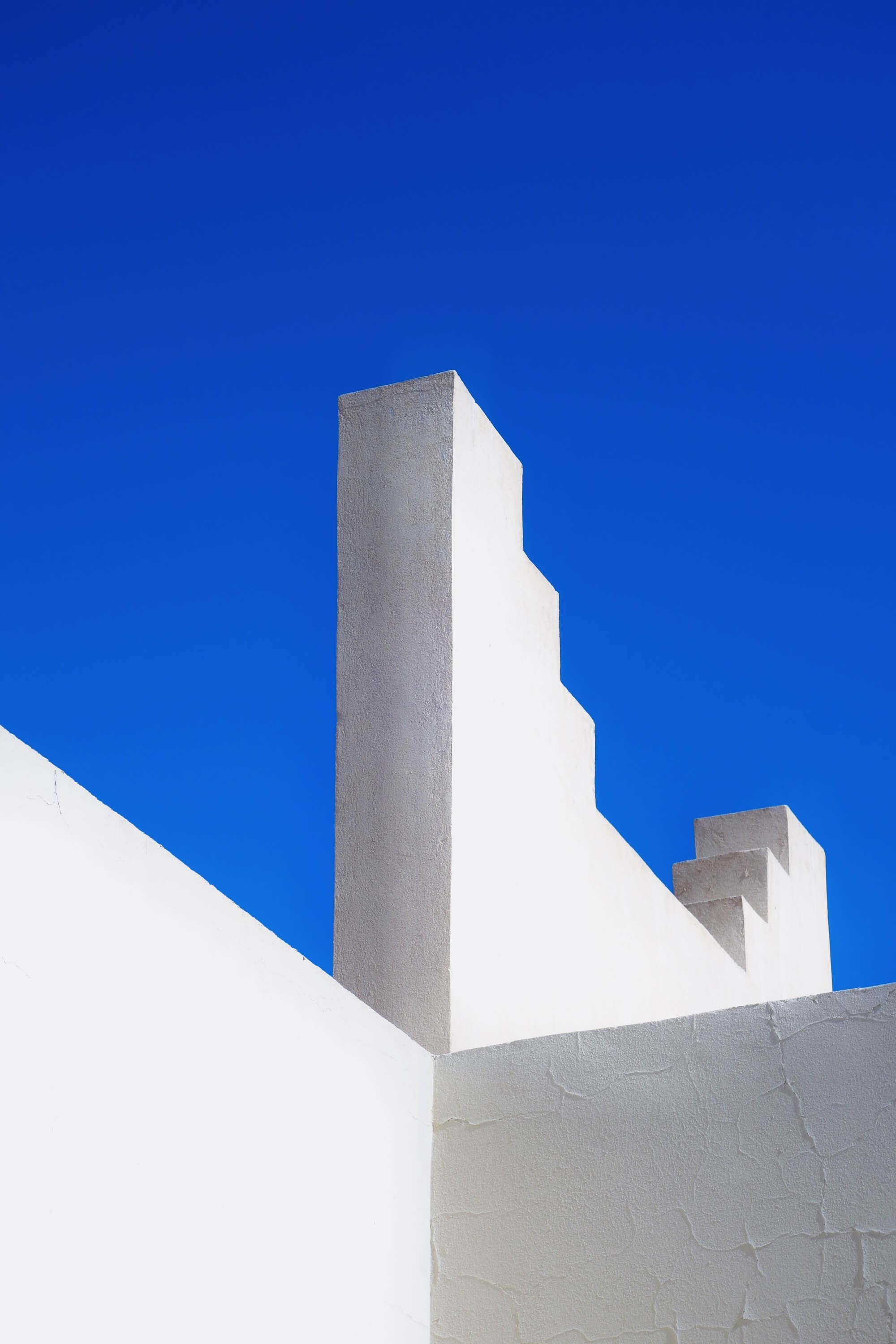 Künstlerische Aufnahme einer weißen Mauer vor strahlend blauem Himmel